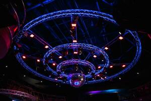 discoteca noturna com luz vermelha violeta azul néon, bola de espelhos de discoteca e holofotes brilhantes com construção luminosa de armação de metal redonda foto