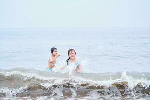 uma Garoto e uma menina estão tendo Diversão jogando dentro a mar. foto