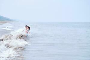 uma Garoto e uma menina estão tendo Diversão jogando dentro a mar. foto