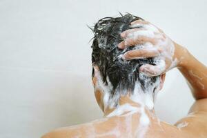 uma homem é lavando dele cabelo com xampu foto