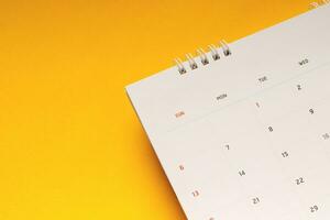 feche a agenda do calendário da vista superior para fazer reuniões de compromisso ou gerenciar o calendário todos os dias em fundo amarelo para planejar o trabalho e o conceito de viagem. foto