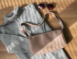 pequena bolsa de couro bege e suéter feminino cinza