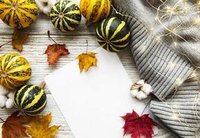 folhas de bordo de outono, abóboras e lenço de lã em um fundo de madeira.