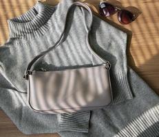 pequena bolsa de couro bege e suéter feminino cinza