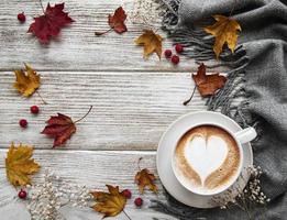 xícara de café e folhas secas em fundo branco de madeira
