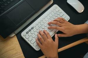 topo visualizar. mão do empresária digitando em teclado e trabalhando computador portátil em de madeira mesa às lar. empreendedor mulher trabalhando para dela o negócio às vivo quarto lar. o negócio trabalhos casa conceito. foto