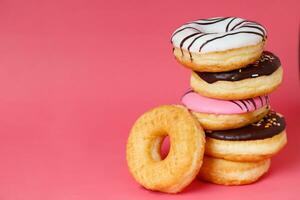 sortido rosquinhas com chocolate geada, cobertura granulados rosquinhas colorida variedade e variedade do sabores misturar do multi colori doce rosquinhas com fosco borrifado em Rosa fundo. topo Visão foto