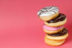 sortido rosquinhas com chocolate geada, cobertura granulados rosquinhas colorida variedade e variedade do sabores misturar do multi colori doce rosquinhas com fosco borrifado em Rosa fundo. topo Visão foto