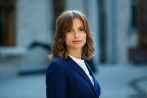 retrato do uma bem sucedido o negócio mulher dentro frente do moderno o negócio prédio. jovem Gerente poses fora. mulher empregado do a escritório. foto