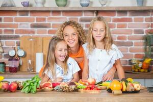mãe e filhas cozinhando juntos dentro a cozinha. saudável Comida conceito. retrato do feliz família com fresco batidos. feliz irmãs. foto