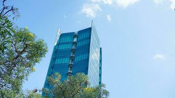 inferior Visão azul óculos construção com céu e nuvem fundo. arranha-céu, Visão do moderno o negócio prédio. brincar moderno azul óculos construção panorama. olhando acima perspectiva. cópia de espaço foto