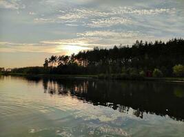 lago e floresta dentro pôr do sol, pitoresco papel de parede foto