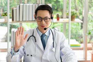 médico asiático dá consulta ao paciente por videochamada online foto