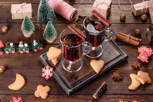 Natal quente com vinho tinto com especiarias e frutas em uma mesa escura. foto