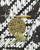 uma batik tecido com uma rattan esteira, uma raminho do trigo, e edelweiss flores natureza fundo. foto