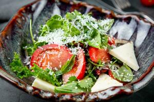 salada com tomates, feta queijo, alface e salsinha dentro a incomum tigela lado Visão foto