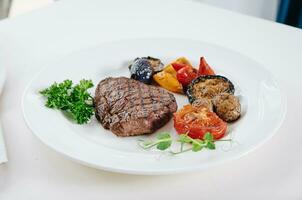 carne bife com grelhado legumes e ervas em uma luz fundo foto