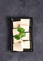 tofu fatias com salsinha em isto em uma Preto prato foto