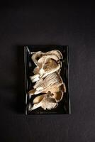 fresco e cru ostra cogumelos em uma Preto prato Visão a partir de acima foto