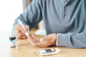 homem usa lanceta no dedo para verificar o nível de açúcar no sangue pelo medidor de glicose foto