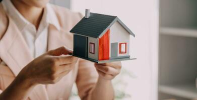 corretor de imóveis entrega uma amostra de uma casa modelo ao cliente, contrato de empréstimo hipotecário fazendo aluguel e comprando uma casa e contratando o conceito de seguro residencial foto