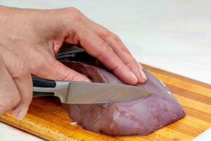 mulher mão corte carne fígado em corte borda foto