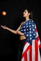 retrato fêmea atleta embrulhado dentro americano bandeira contra Preto fundo foto