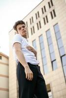 bonito jovem hipster à moda homem dentro branco camisa, Preto calça foto