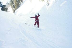 ativo snowboarder pulando dentro montanhas em uma ensolarado dia foto