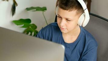 casa Aprendendo conceito. adolescente Garoto parece às computador monitor vestindo fones de ouvido. foto