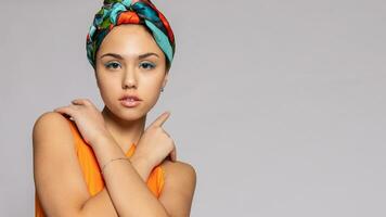 retrato do uma jovem mulher com brilhante Maquiagem e uma elegante lenço de cabeça. foto