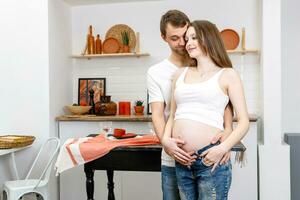 jovem casado casal abraços em pé perto mesa dentro cozinha. foto