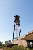 uma lindo água torre é conjunto por aí a abandonado área. isto oxidado metal estrutura carrinhos alta contra uma azul céu. foto