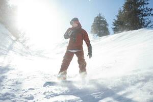 ativo snowboarder pulando dentro montanhas em uma ensolarado dia foto