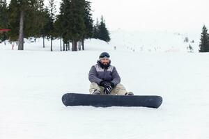 snowboarder sentado às a topo do uma montanha foto