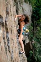 uma menina sobe uma Rocha. mulher acionado dentro extremo esporte. foto