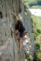 uma menina sobe uma Rocha. mulher acionado dentro extremo esporte. foto