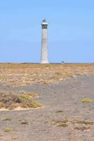 uma farol em uma estéril campo com uma azul céu foto