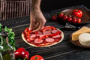 cozinhar dentro a cozinha colocando a ingredientes em a pizza. pizza conceito. Produção e Entrega do Comida. foto