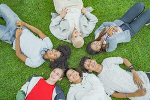 topo ângulo Visão do multiétnico jovem na moda amigos sorridente e fazer uma círculo dentro a Relva foto