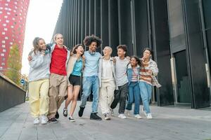 alegre grupo do jovem feliz amigos caminhando baixa a rua segurando cada de outros carinhosamente. foto