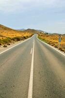 uma estrada placa dentro a deserto com uma estrada dentro a fundo foto