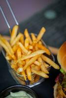 fechar acima do francês fritas e Hamburger dentro cesta em mesa. foto