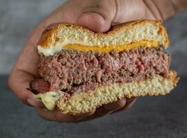 sanduíche com carne bovina, queijo e molho dentro uma mulher mão foto