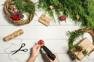 Natal feito à mão faça você mesmo fundo. fazer construir natal guirlanda e enfeites. topo Visão do branco de madeira mesa com fêmea mãos. foto