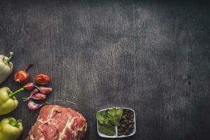 cru carne de porco carne em uma Sombrio de madeira superfície e ingredientes para culinária. Comida fundo com cópia de espaço. foto