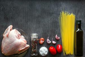 massa ingredientes. frango seios, cereja tomates, espaguete massa, óleo, especiarias e alho em a de madeira mesa. espaço para texto. foto