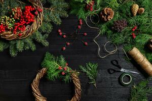 faço uma Natal guirlanda com seu próprio mãos. abeto filial, Natal guirlanda e presentes em uma Preto de madeira fundo foto