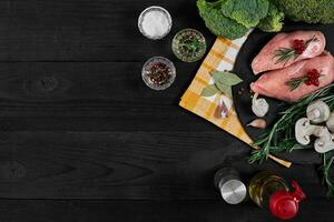 cozinhando frango seios. em a mesa estão especiarias - alecrim, vermelho e Preto pimenta, cogumelos, brócolis. conceito - saudável Comida. foto