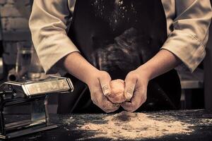 a chefe de cozinha faz massa para massa em uma de madeira mesa foto